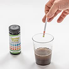 Dipping Garden Tutor 3 Pad pH test strip into soil water mixture